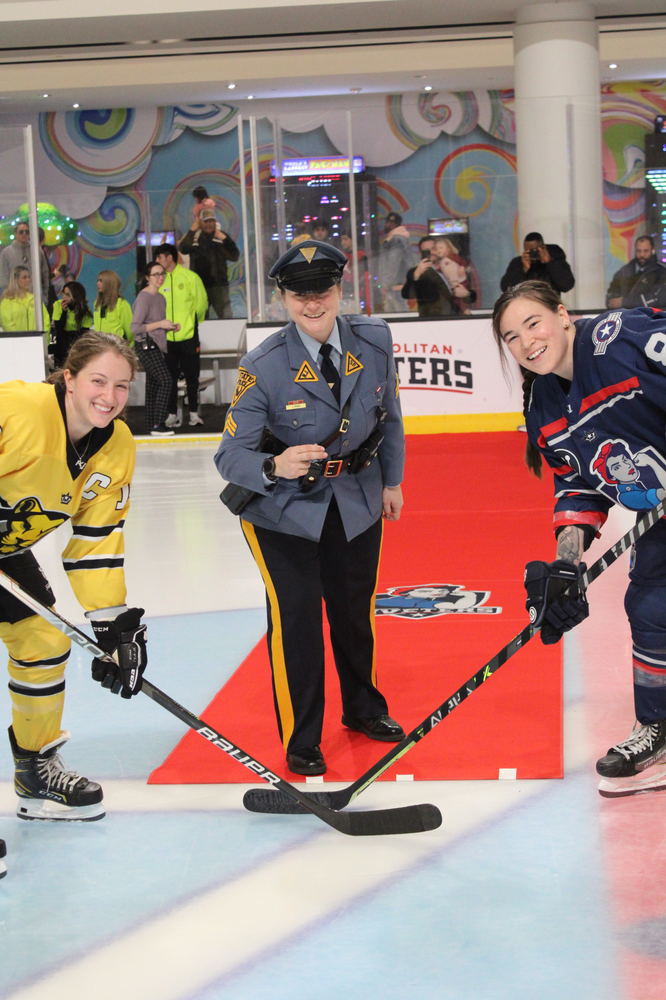 Metropolitian Riveters Forward Kelly Babstock takes the ceremonial puck drop with Boston Prides Loren Gabel. NJ State Trooper drops the puck.