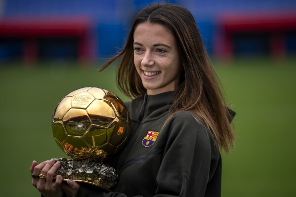 Aitana Bonmatí holds her Ballon d'Or Féminin trophy while wearing Barcelona training kit at team facility