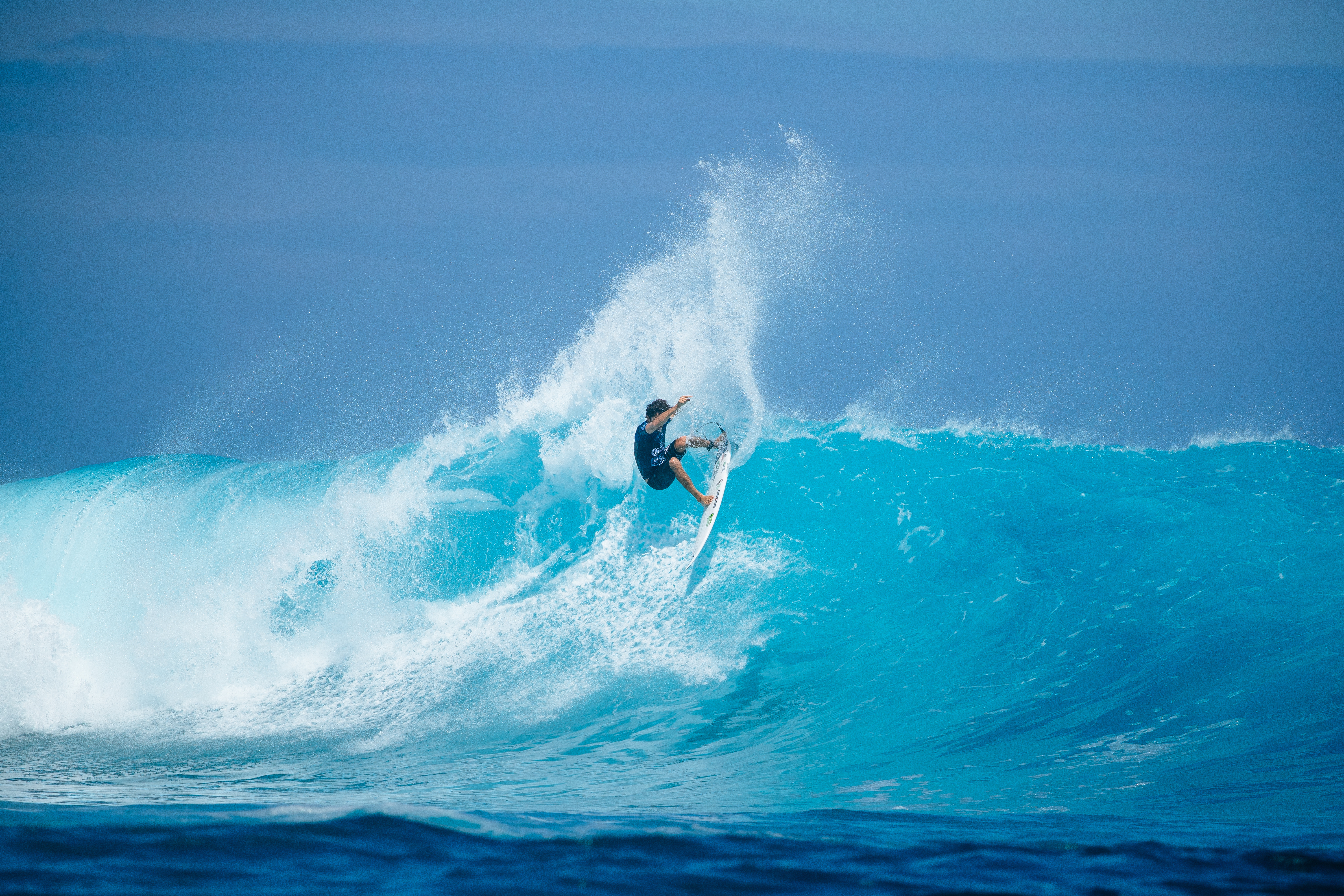 Yago Dora performs aerial maneuver creating massive spray while surfing blue wave in Fiji during 2024 competition