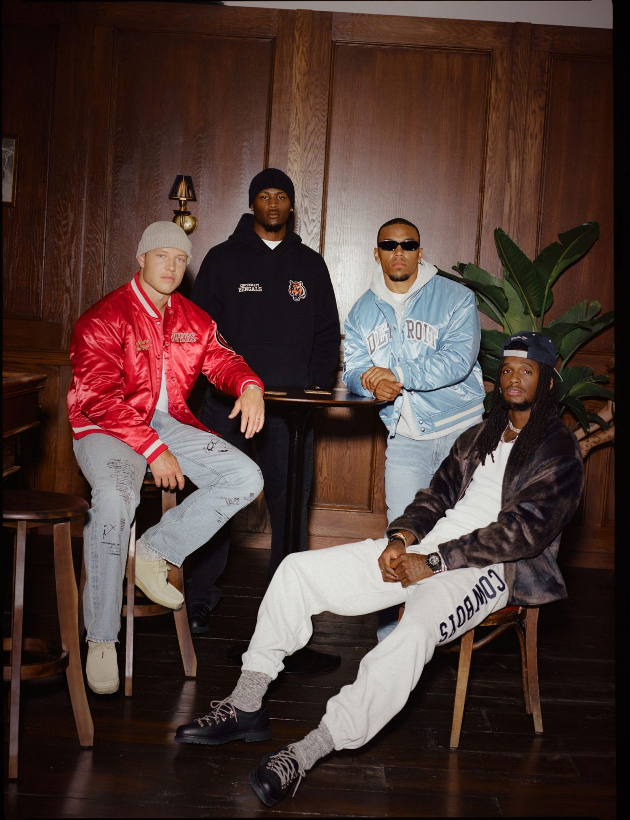 Four NFL athletes Christian McCaffrey (San Francisco 49ers) Amon-Ra St. Brown (Detroit Lions) CeeDee Lamb (Dallas Cowboys) Tee Higgins (Cincinnati Bengals) modeling Abercrombie & Fitch custom apparel in a luxury wood-paneled interior setting, showcasing the brand's new NFL partnership collection