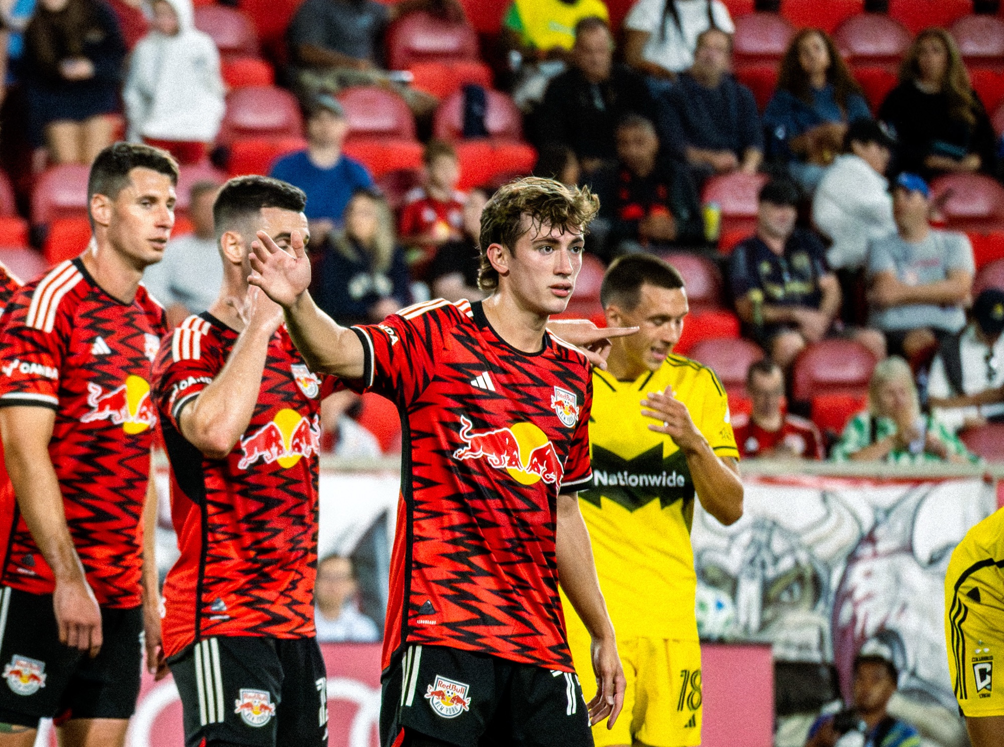 New York Red Bulls players Daniel Edelman, Sean Nealis, and Dylan Nealis position themselves defensively while awaiting a Columbus Crew corner kick at Red Bull Arena with crowd in background