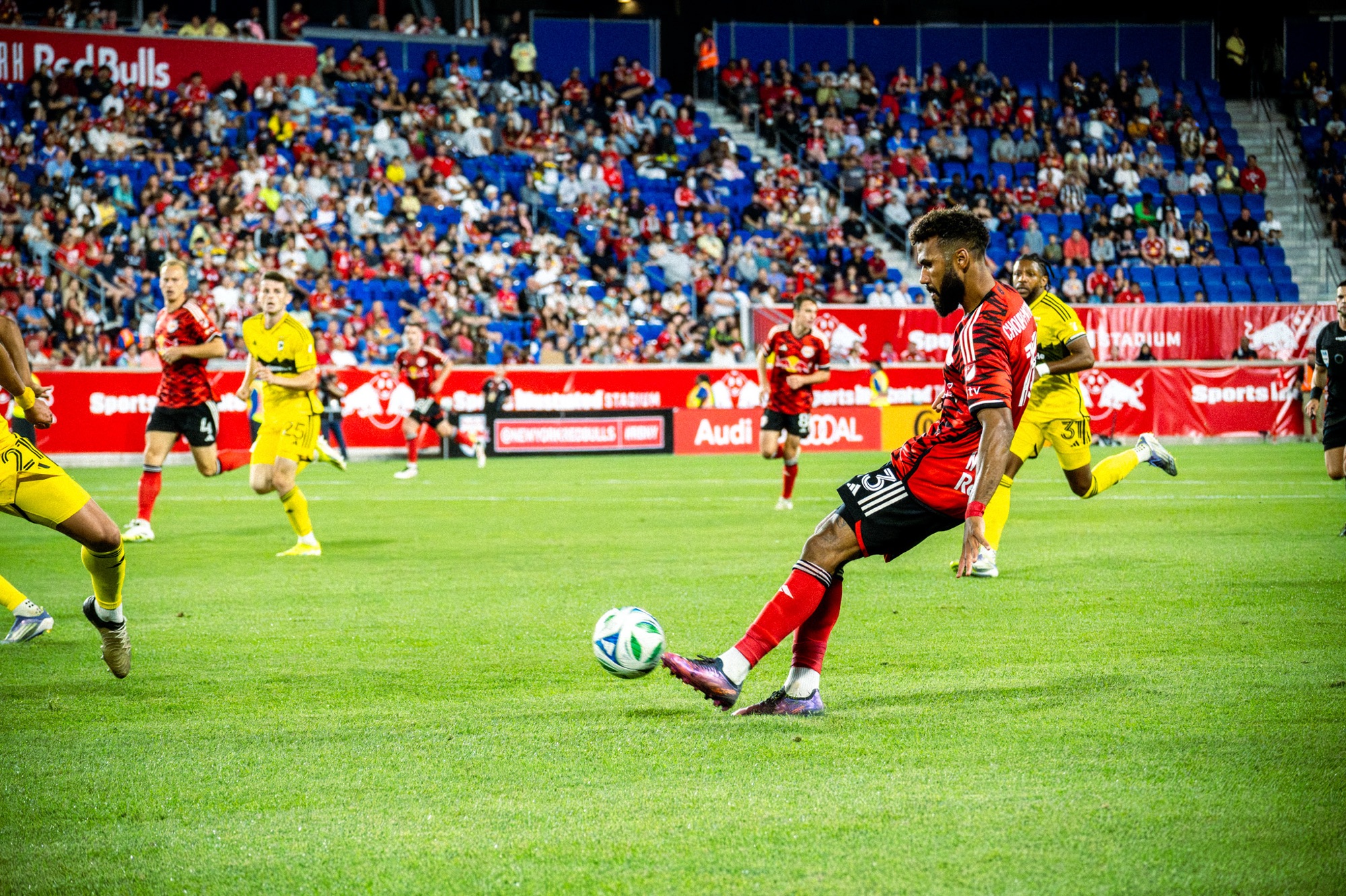 New York Red Bulls forward Eric Maxim Choupo-Moting attempts to play a pass through Columbus Crew defenders during MLS match at Red Bull Arena with crowd in background