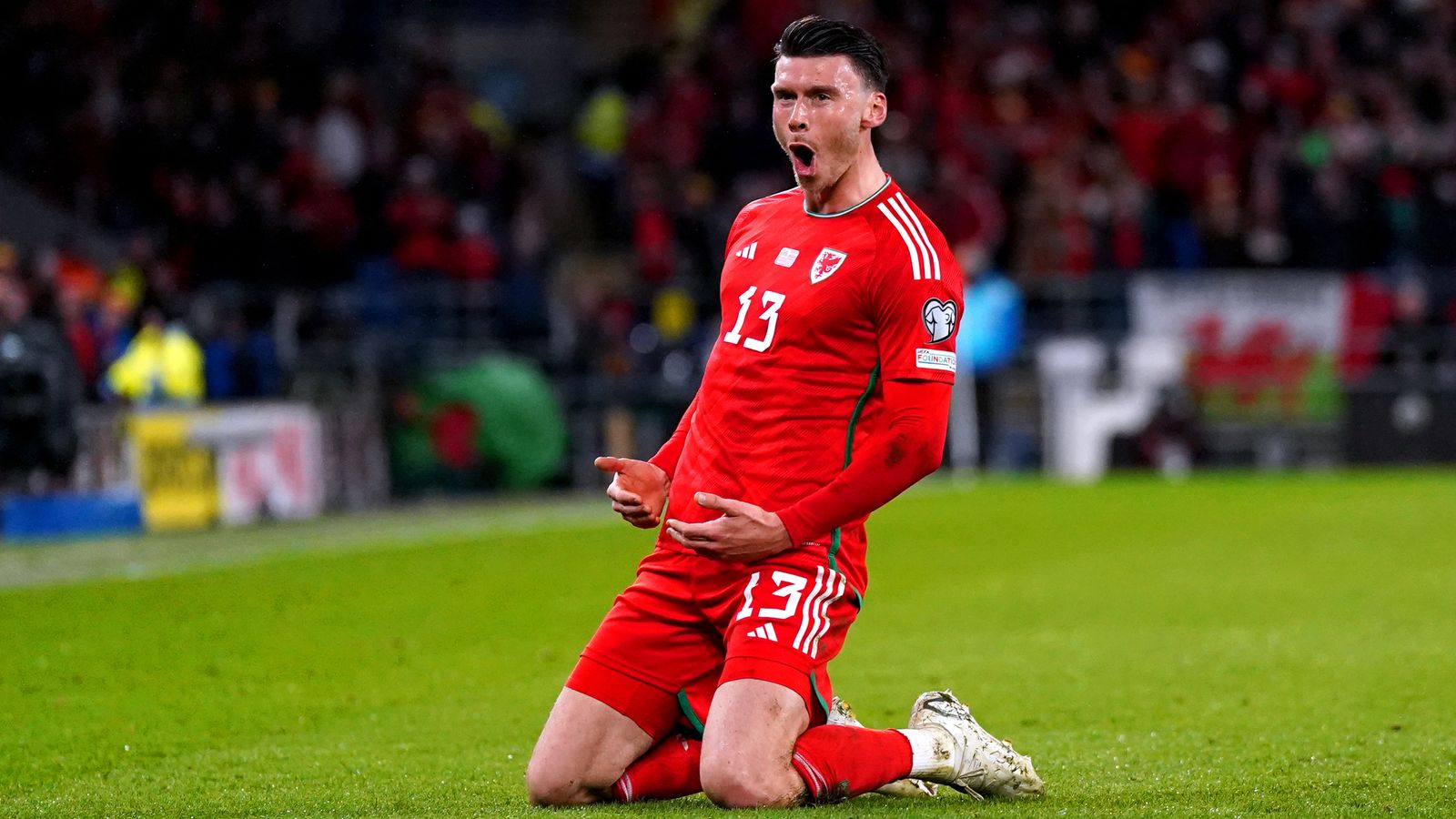 Kieffer Moore celebrates in Wales red jersey number 13 during international match