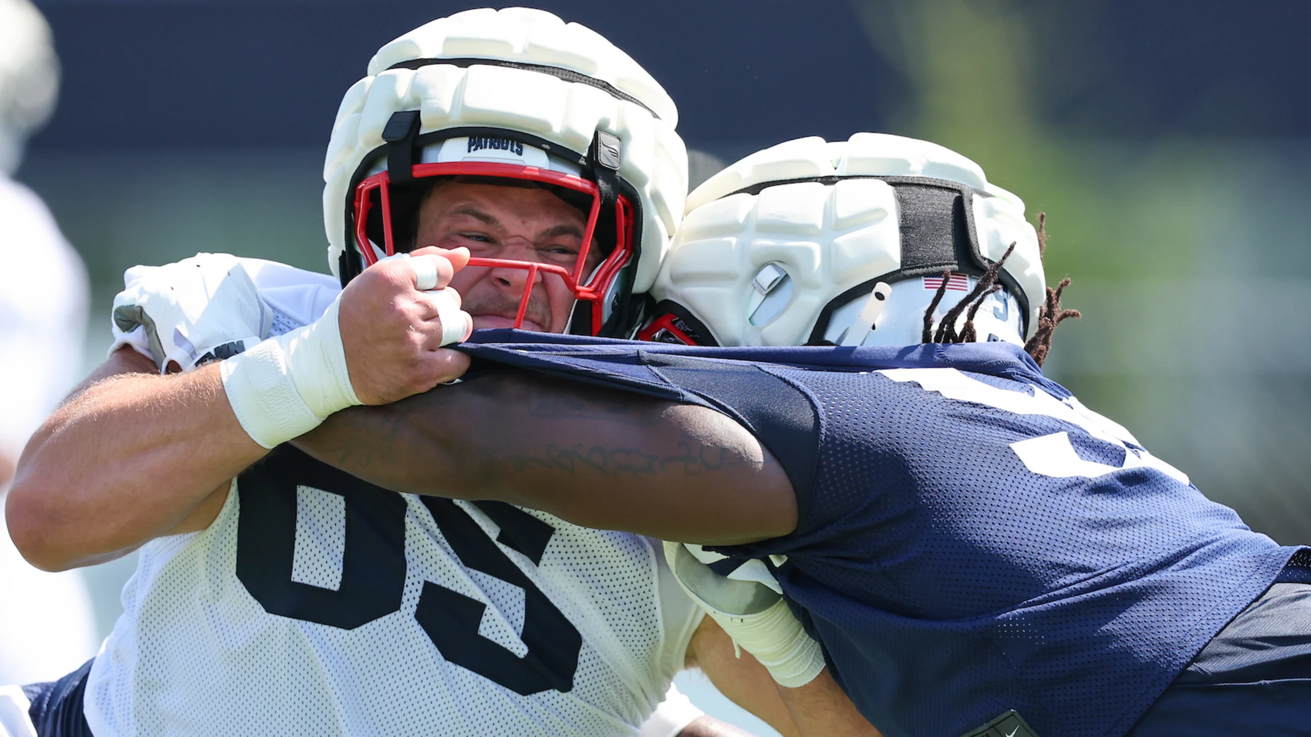 Patriots players engage in blocking drill during training camp practice with intense physical contact