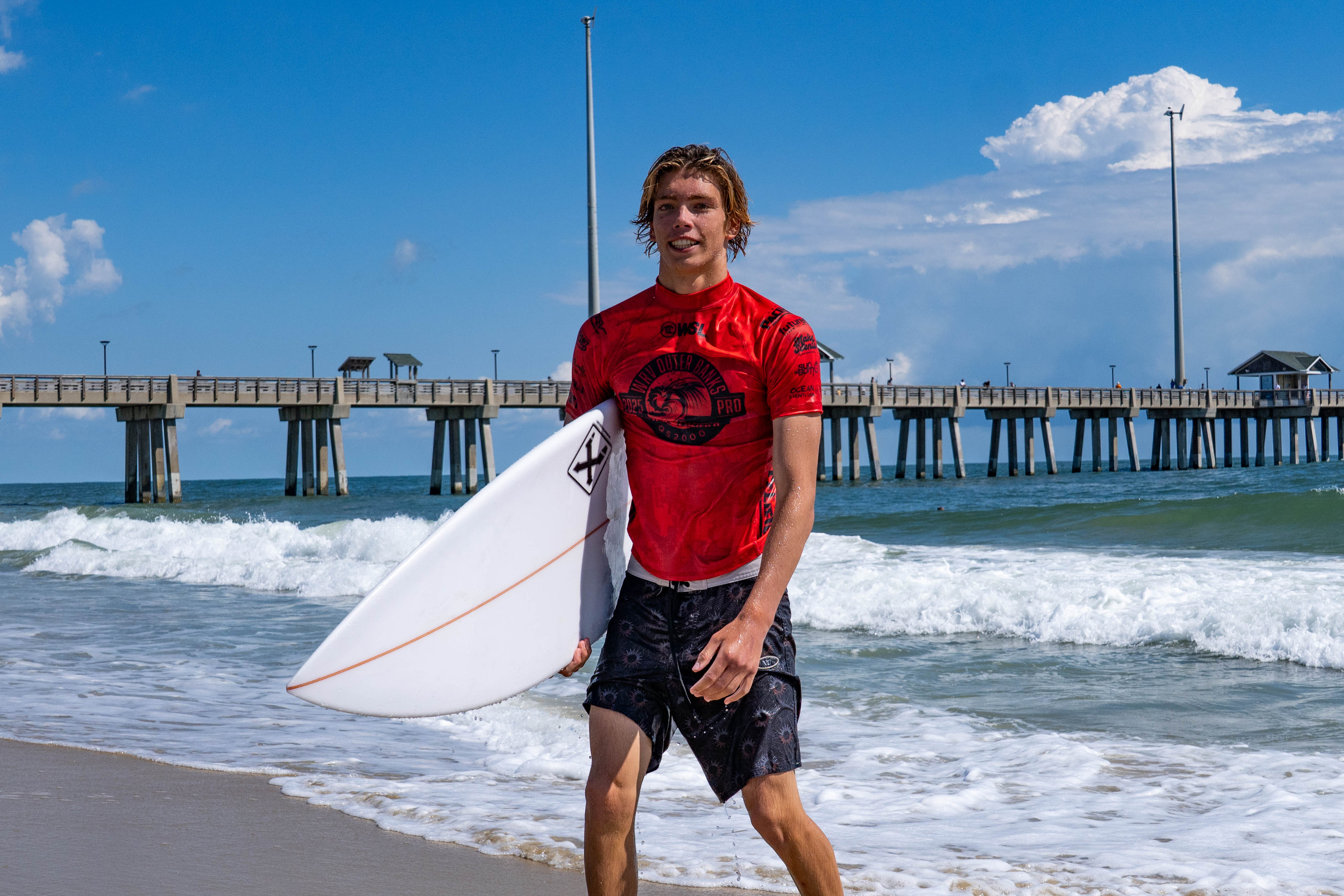 Luke MacBeth poses with surfboard at Jennette's Pier after scoring excellent 8.00 at WRV Outer Banks Pro