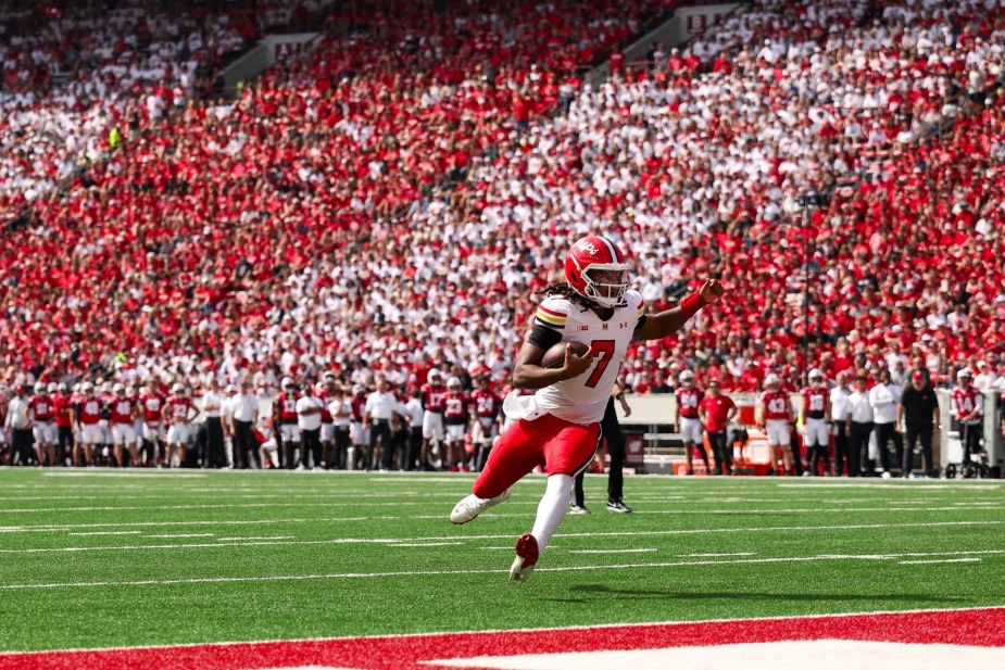 Maryland quarterback Malik Washington (#7) runs into the end zone for a touchdown against the Wisconsin Badgers with a massive crowd at Camp Randall Stadium in the background