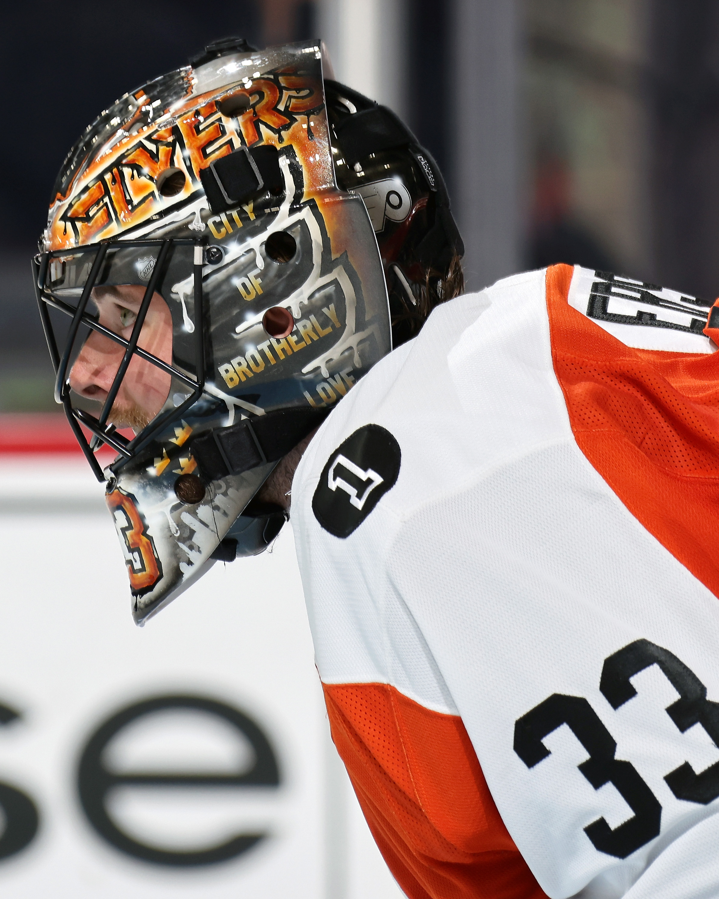 Philadelphia Flyers goaltender Samuel Ersson #33 wearing custom painted Flyers-themed goalie mask with orange and black design during NHL game