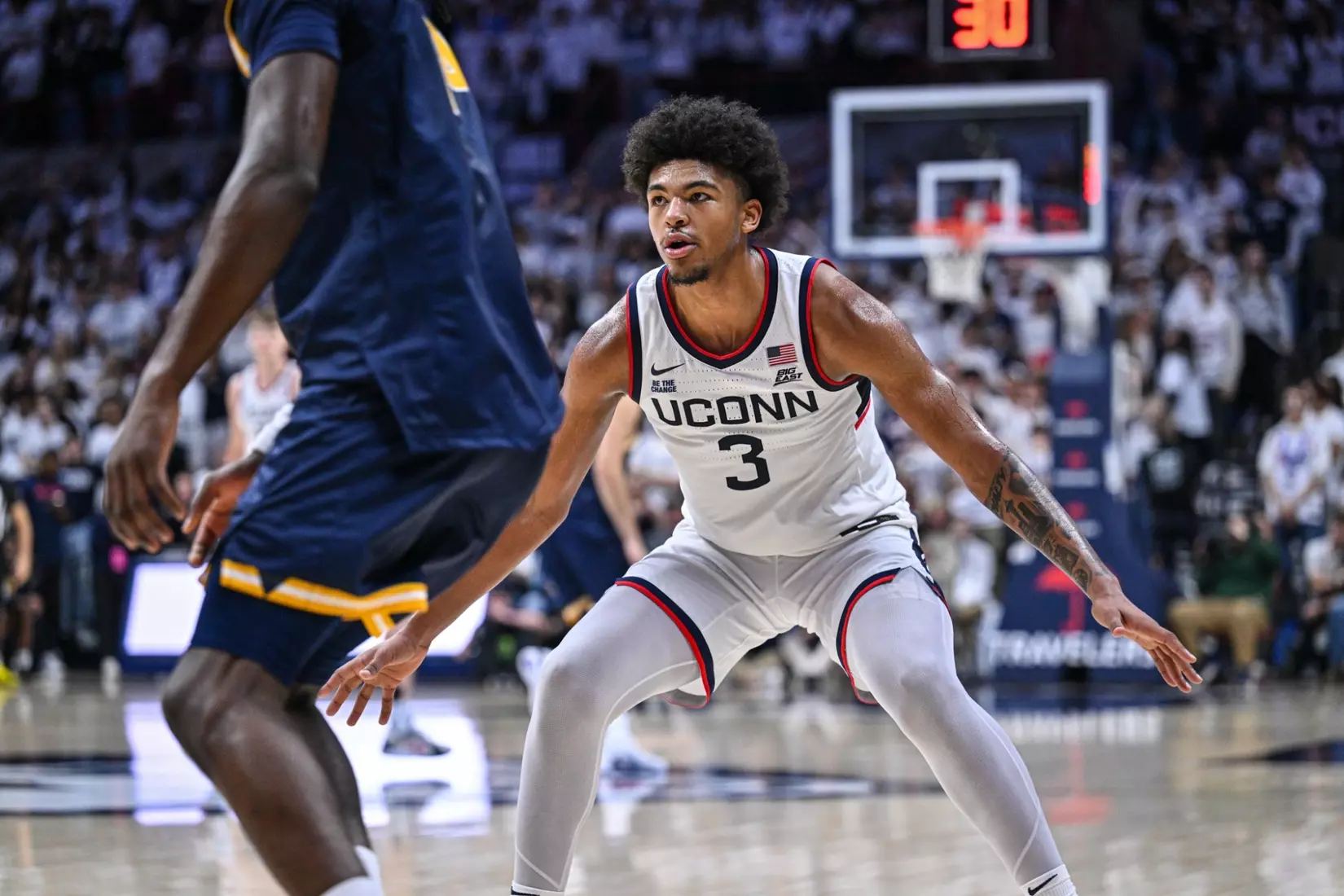 UConn Huskies guard number 3 drives one-on-one against New Haven Chargers defender at top of key during 77-59 season opener win at Gampel Pavilion November 3 2025
