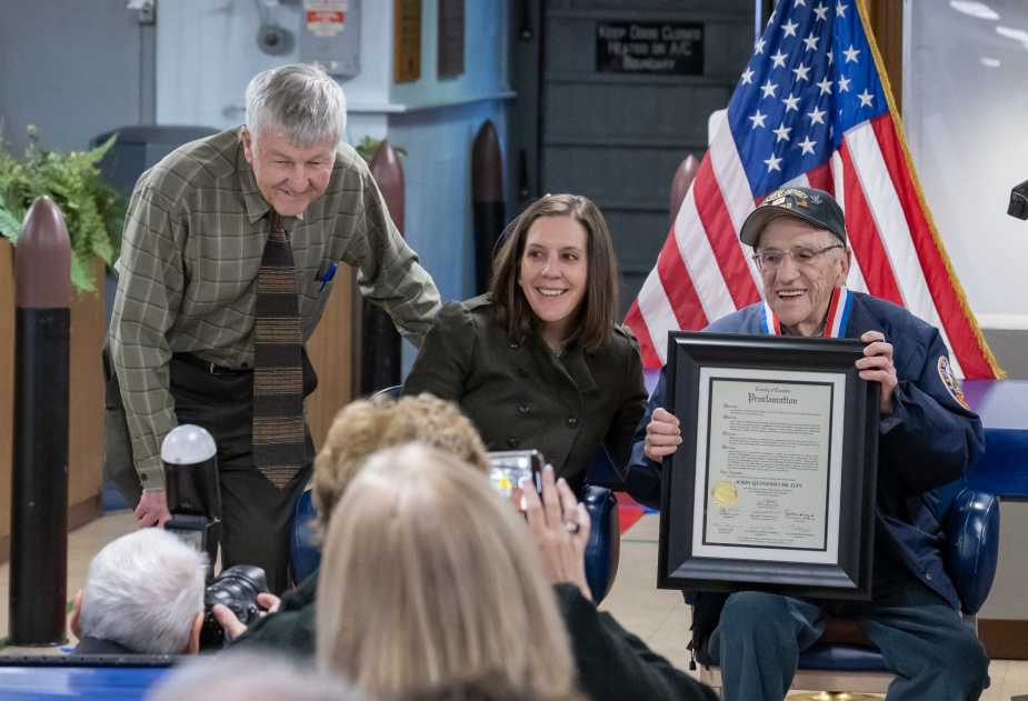 WWII Navy veteran John “Johnny Q” Quinesso Sr. smiles while holding a framed proclamation during his 100th birthday recognition ceremony aboard the Battleship New Jersey Museum in Camden, N.J.